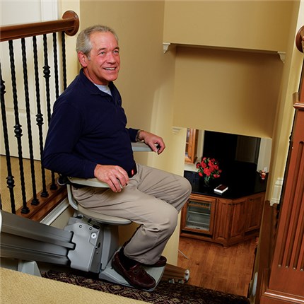 senior man using stair lift to safely get down the stairs