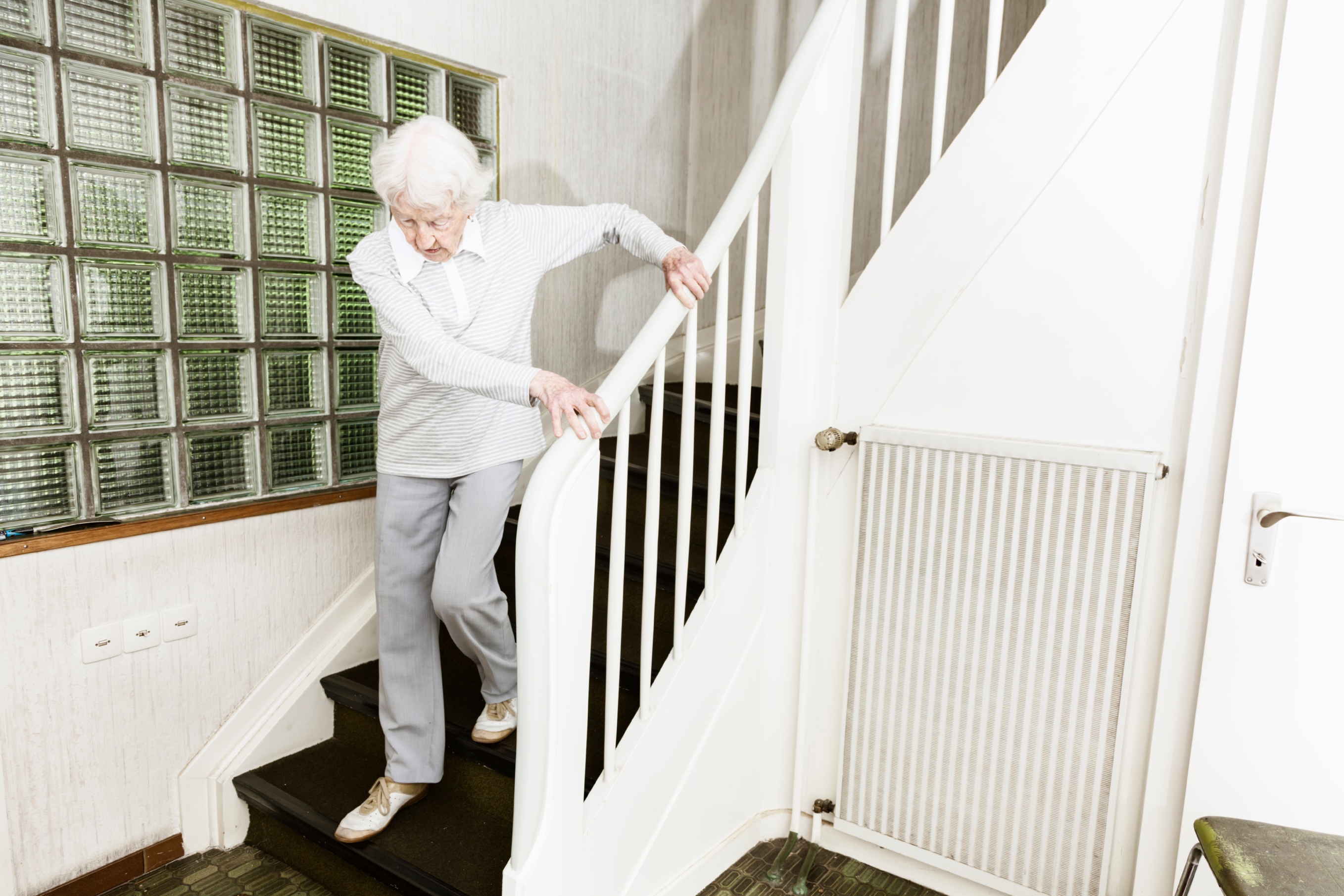 senior woman struggling to get down the stairs in her home