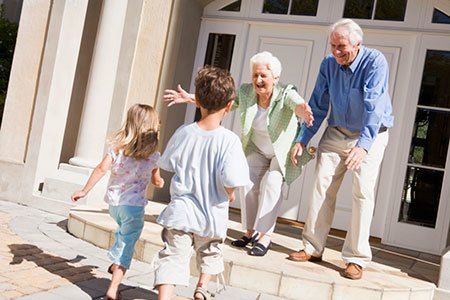 seniors embrace grandchildren on their front step of home