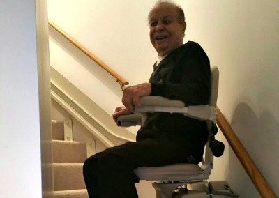 Man riding a curved Bruno stair lift at home