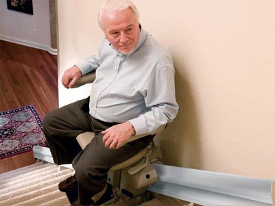 grandpa riding his new stair lift down to the main floor level of his home