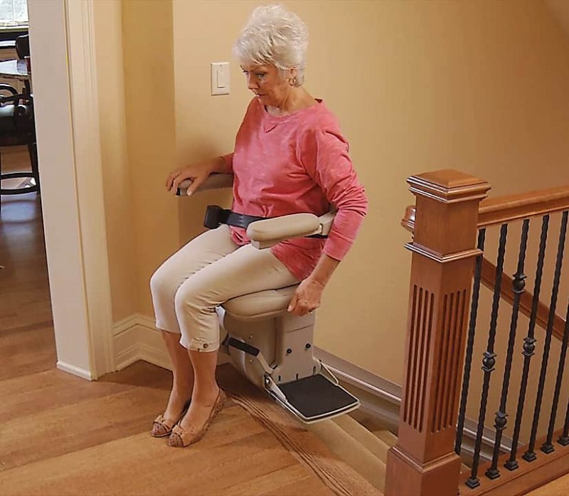 woman safely exits stairlift at top landing of staircase