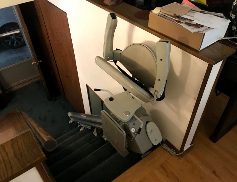 newly installed stairlift in Minnesota home with arms seat and footrest folded up at top landing