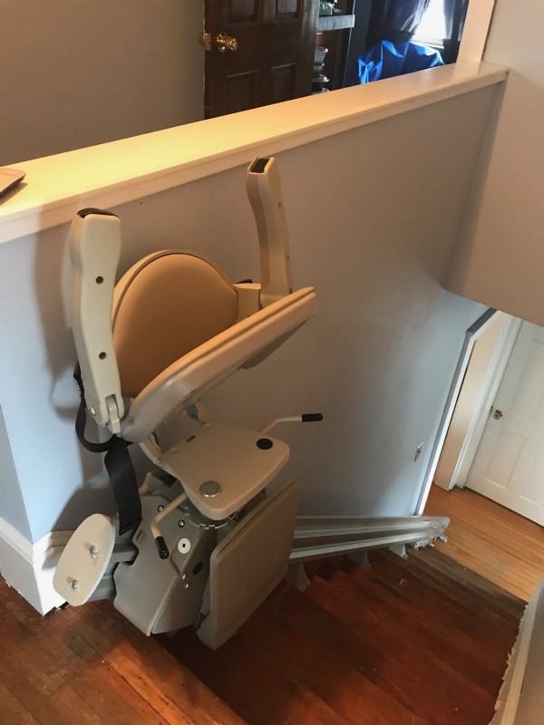 stair lift with components folded up at top landing of stairs in Havervill Massachuetts