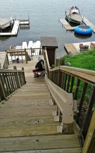 Image of a man riding down a stair lift that was installed on the stairs in his backyard in Round Lake, Illinois