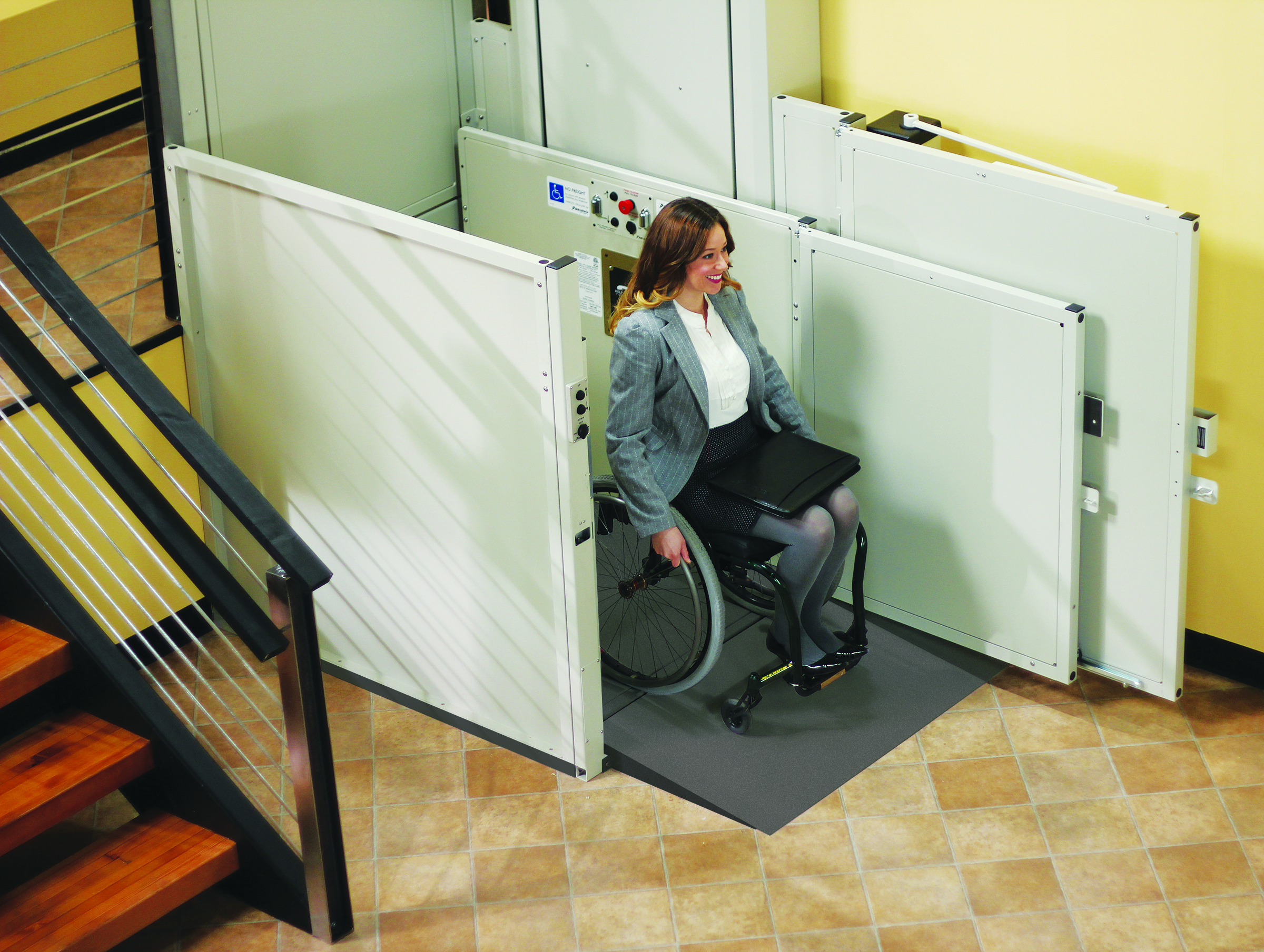 woman in a wheelchair exiting a commercial wheelchair lift in her office building
