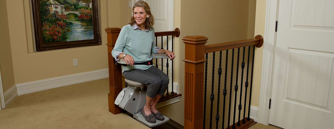 woman on Bruno Elan stair lift at the top of the staircase