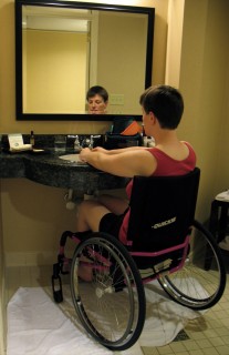 young man in wheelchair using roll-under sink to wash his hands